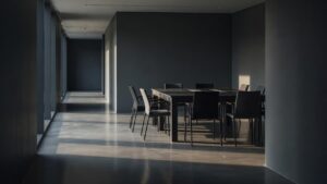 A narrow office corridor with charcoal walls and light-toned floors illuminated by early morning sun.