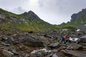 A person walking forward along a difficult rocky path, representing growth after a leadership setback.