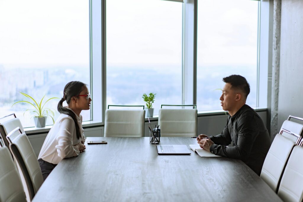 Two colleagues discussing a workplace problem across a conference table.