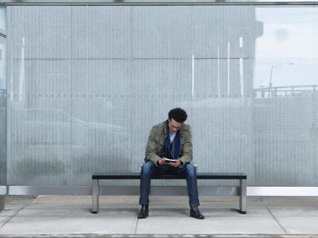 Person checking a phone during a quiet moment, representing the impulse to fill empty space with stimulation.