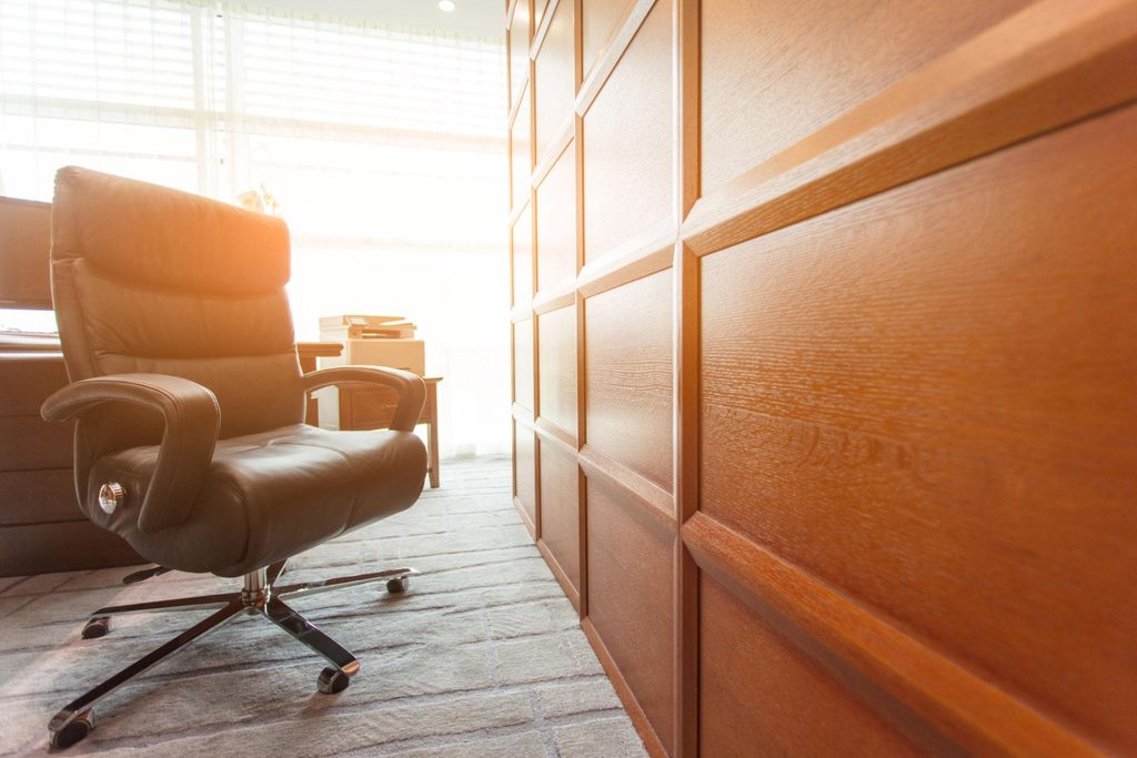 An empty office chair beside a desk in morning sunlight, representing the leadership role someone else will eventually fill.